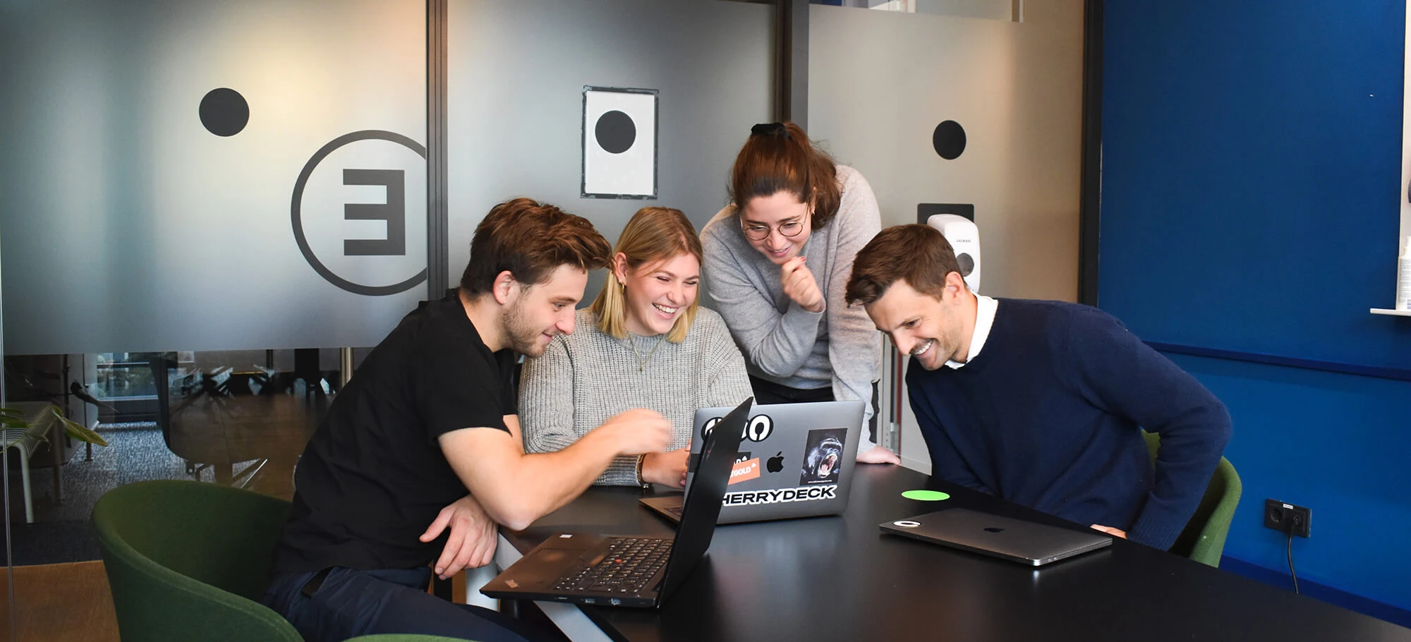 Team members laughing around a laptop